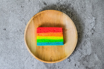 Top view of one rainbow cake on the wooden plate. Grey or gray Cement. Background. colourful. Colorful. High angle, above, flat lay, Close up.