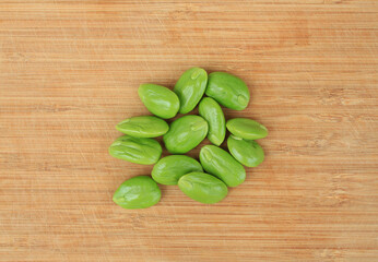 Stink beans (Parkia speciosa) on wooden background. Top view.