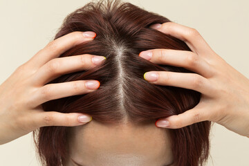 Naklejka premium 若いアジア人の女性は頭皮をマッサージしています。