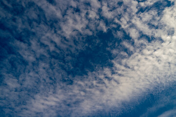 Blue sky with fluffy clouds background. Bright blue sky background. Cloudscape with white clouds. Calm sky on a sunny day. Sunlight through the clouds wallpaper. Spring sky with soft clouds.