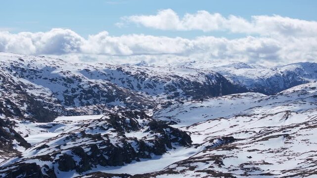 Smooth side-tracking aerial view of Matrefjellene in spring, highlighting rugged peaks with lingering snow