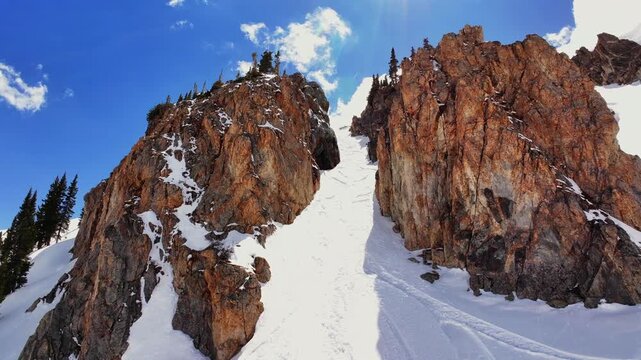 Spring cornice rock walls chute Deer Creek Trail Montezuma winter Rocky Mountain Colorado avalanche terrain aerial drone sunny blue sky deep powder snow snowmobile ski snowboard backcountry forward up