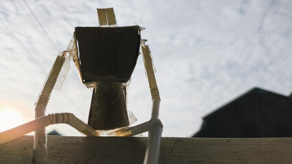 Recycled humanoid craft made of bendable straws and paperboard, laying across a scratched wooden surface. DIY artistic representation of zero waste creativity and repurposed toys.