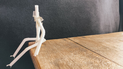 Homemade straw puppet made of cardboard and plastic on textured wooden table. DIY eco-friendly art...