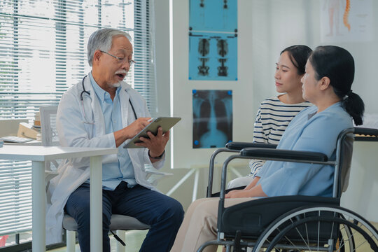 Asian daughter accompanies senior mother for medical consultation with doctor using digital health technology. Family centered care demonstrates intergenerational support and patient advocacy through