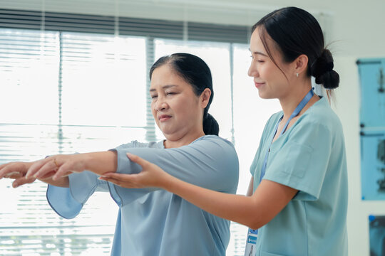 Physiotherapist aids senior recovery through evidence-based rehabilitation and therapeutic humor approach. Medical team demonstrates patient-centered orthopedic care for osteoporosis and arthritis
