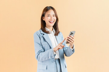 Asian businesswoman holding smartphone isolated against a beige background.