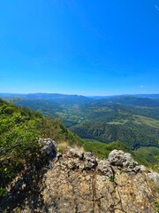 View from rocky Bedeleu Mountain top over the mountains and Aries Valley nearby. High cliff over green forest on a sunny summer day. Salciua, Alba, Romania
