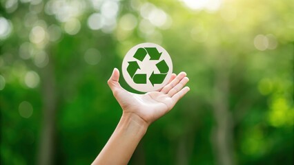 Close-up of hand with recycling icon on blurred green background — symbolizing environmental care