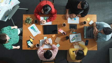 Top view of businesswoman sharing idea while stand at white board while manager asking question at table with tablet display financial graph. Attractive female leader pointing at board. Convocation.
