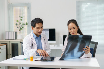 Two doctors examining a chest x ray, discussing diagnosis and treatment options in a bright, modern hospital office filled with technology