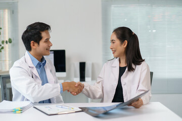 Obraz premium Two doctors shaking hands after successfully diagnosing a patient using an x ray image in a modern hospital room