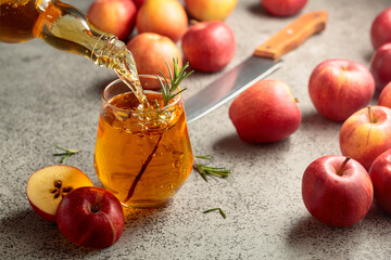 Apple cider is poured from a bottle into a glass.