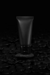 Black plastic cream tube with stone for mockup on black background. Selective Focus.