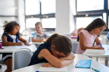 Obraz na płótnie Canvas Exhausted child struggling with schoolwork at school.