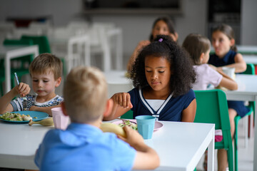 Kids in school eating in canteen, having healthy lunch.