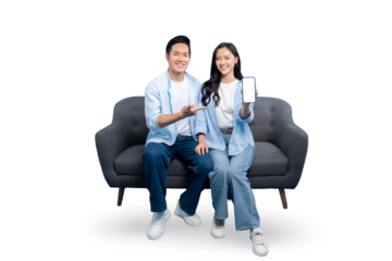 A happy couple sitting on sofa, smiling while holding the smart phone