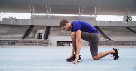 Man, athlete and ready with start line on stadium track for sprint, race or training lap. Active, male person or runner in preparation with begin for sport competition, distance running or fitness