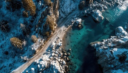 Aerial view of snow-dusted coastal road meeting teal water