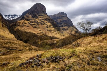 River Coe flows through Glen Coe with The Three Sisters mountains in early spring, Scotland