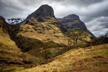 River Coe flows through Glen Coe with The Three Sisters mountains in early spring, Scotland