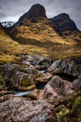 River Coe flows through Glen Coe with The Three Sisters mountains in early spring, Scotland