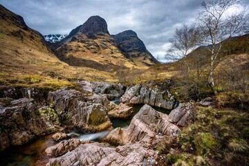 River Coe flows through Glen Coe with The Three Sisters mountains in early spring, Scotland