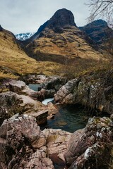 River Coe flows through Glen Coe with The Three Sisters mountains in early spring, Scotland