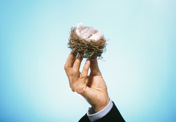 A nest with feathers in the hand of a businessman.