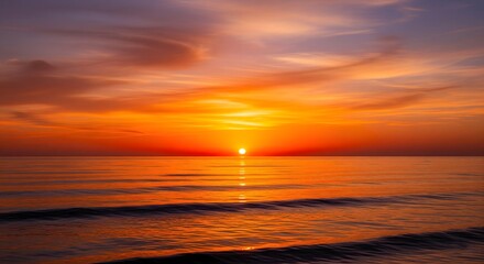 Vibrant orange sunset over calm ocean waters reflecting fiery sky colors