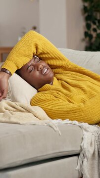 Illness, woman and stomach pain on sofa in home for menstruation, agony or uncomfortable ache. Discomfort, black person or belly cramps with endometriosis, constipation or pelvic inflammatory disease