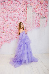 Fototapeta premium A young Caucasian woman with long brown hair wears a flowing purple tulle dress