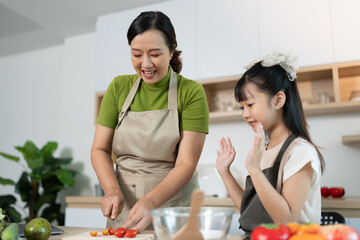 Family Cooking. Smiling mother and daughter chopping vegetables in a bright kitchen.