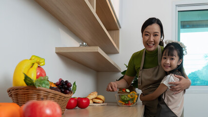 Healthy Cooking. Mother and daughter preparing fresh salad together in modern kitchen.