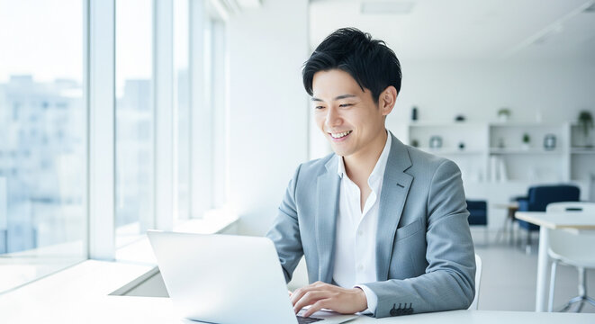 オフィスでパソコン作業をする笑顔の若いビジネスマン