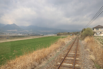 March 26 2025 Rural Railway Passing Through Scenic Countryside with Fields and Mountains, Japan