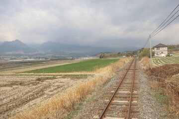 March 26 2025 Rural Railway Passing Through Scenic Countryside with Fields and Mountains, Japan