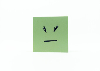 shot of a green sticky note with a hand-drawn angry or frustrated face, centered on a white background.