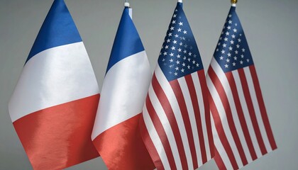 Three upright national flags&mdash;two French flags with vertical blue, white, red stripes, and one American flag with stars and stripes; displayed on flagpoles in a formal setting, suggesting diplomatic or
