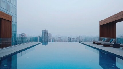 Fototapeta premium Modern Infinity Pool Overlooking Cityscape on a Foggy Day in Urban Environment