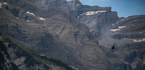 A police helicopter is performing aerial maneuvers over the mountainous terrain of Cauteret in the...