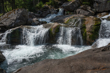 Obraz premium A mesmerizing cascade flows over smooth rocks, framed by lush green trees in the Pyrenees, capturing the tranquil essence of the environment near Pont d'Espagne.