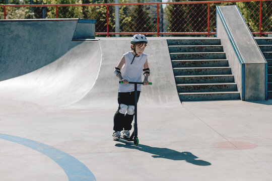 Young Child Riding a Scooter at Skatepark During Summer