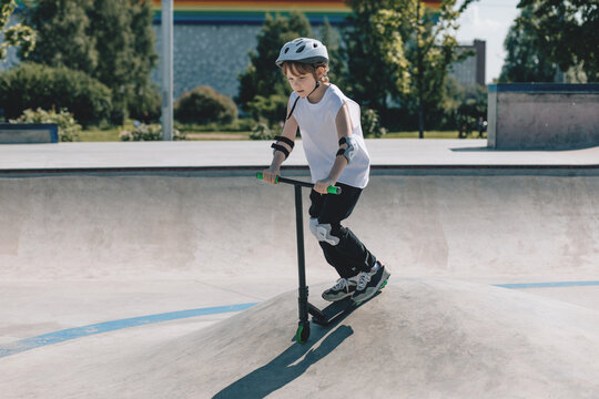 Young Child Joyfully Riding a Scooter at Skatepark During Summer