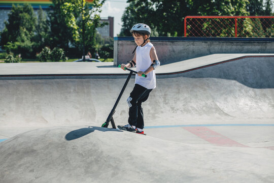 Young Child Joyfully Riding a Scooter at Skatepark Summer