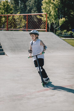 Child Joyfully Riding a Scooter at Skatepark During Summer