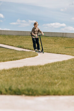 Child Riding a Scooter along a winding path in Park