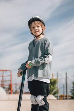 Child with protective gear riding scooter at skate park