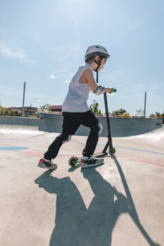 Active Child Scooting at Skatepark Under Bright Blue Sky
