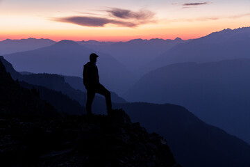 Hiker standing on summit, looking at sunset, success.